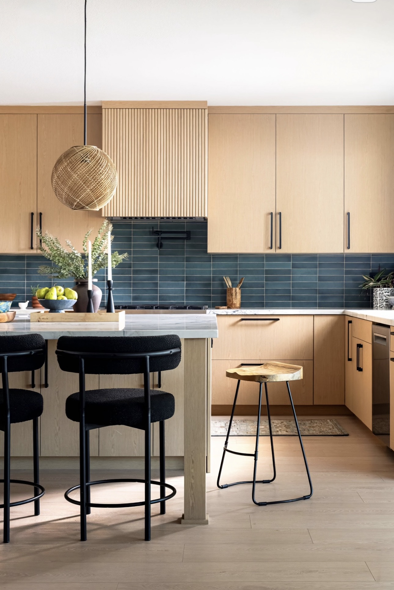 Completed custom kitchen with a marble island, handmade blue tile and rattan pendants