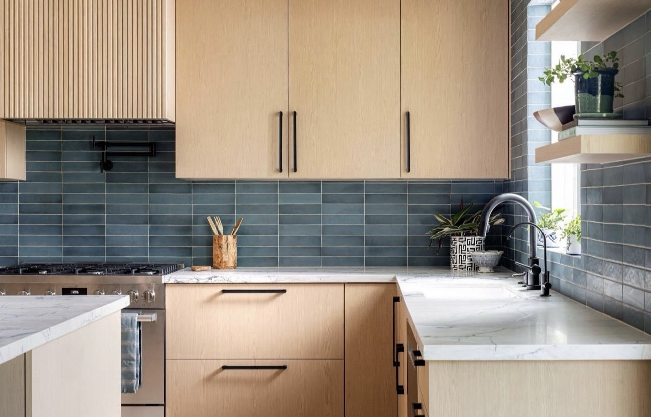 Fluted range hood above handmade tile backsplash and marble counters