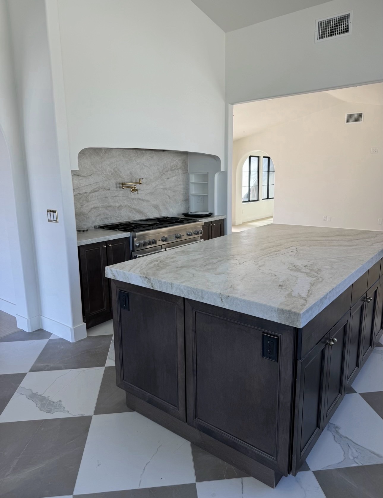 Finished kitchen remodel in the Bonita / Chula Vista area with dark wood cabinetry, a marble island and backsplash, a pro range with brass pot filler, and a checkered tile floor