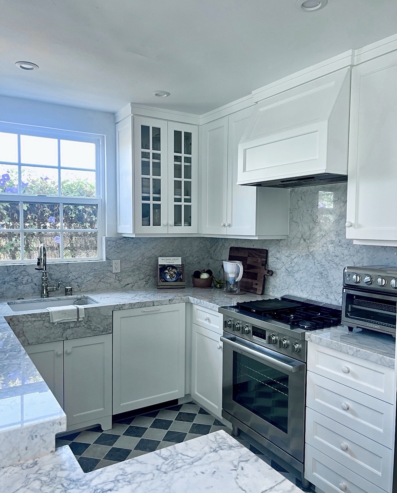 Finished Adams North Park kitchen with white shaker cabinets, marble counters and backsplash, professional range, farmhouse sink and checkerboard floor