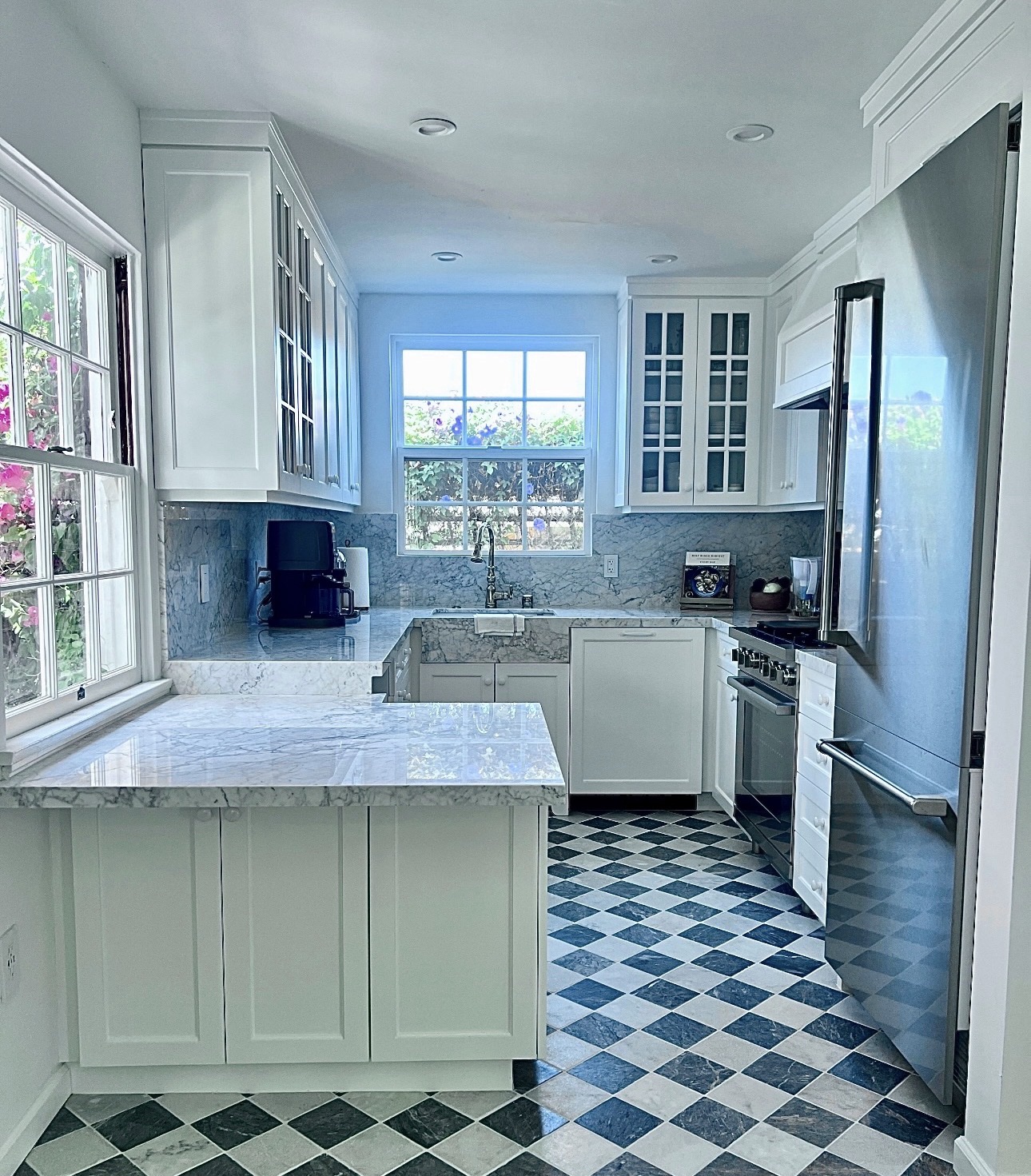 Wide view of the finished Adams North Park kitchen with marble island, glass-front cabinets, stainless steel refrigerator and checkerboard floor