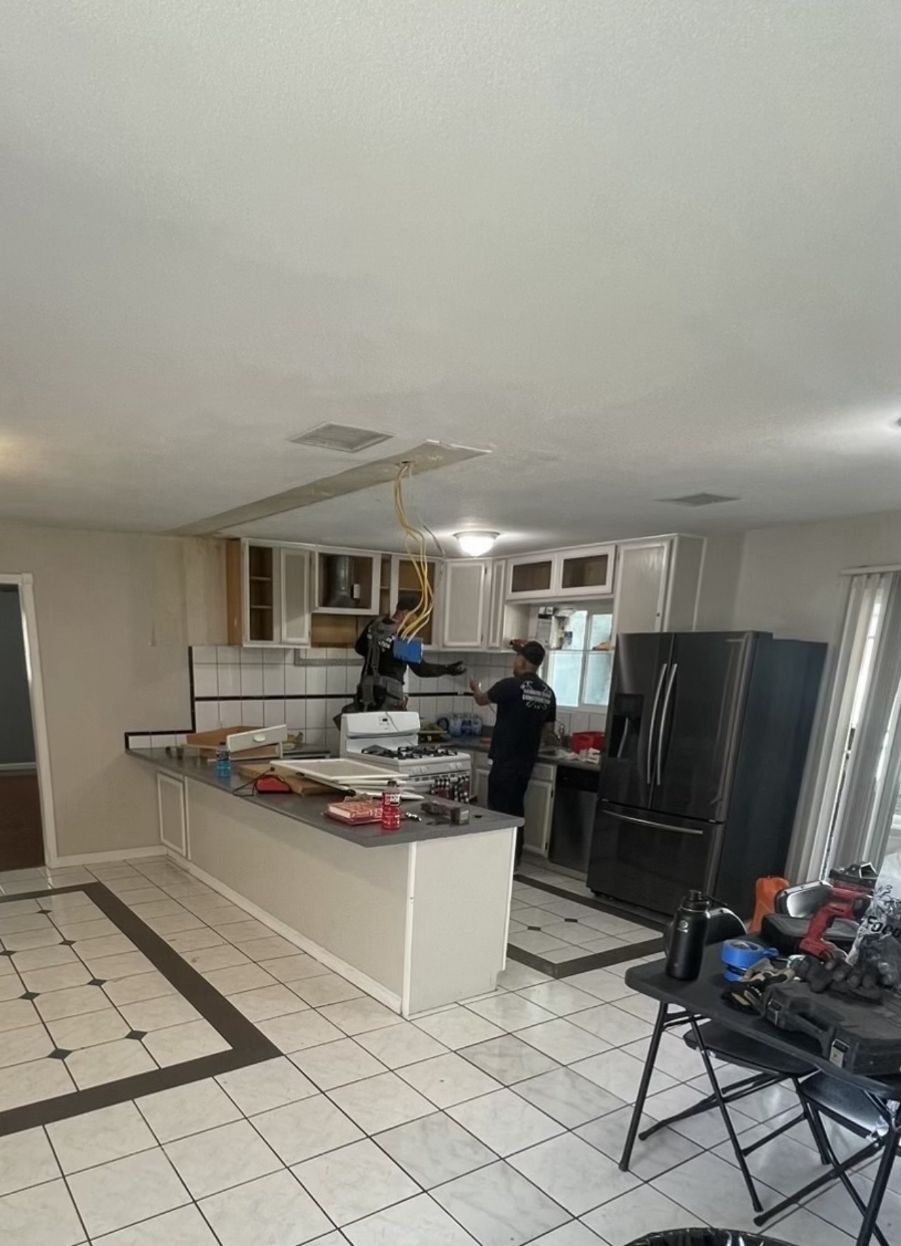 Hammers Down Construction crew member working during demolition as upper cabinets are removed from the family's original kitchen