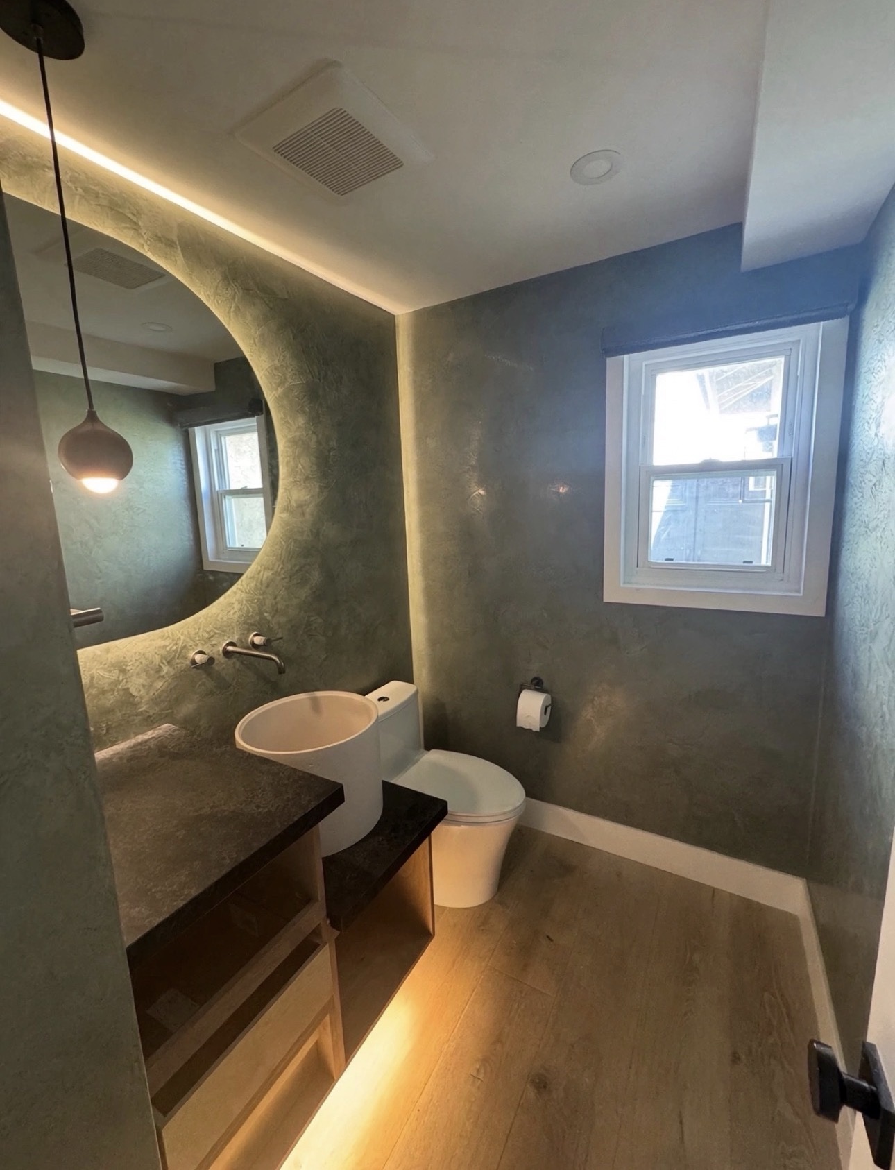 High-end Carlsbad powder room with dark textured walls, a round backlit mirror and vessel sink